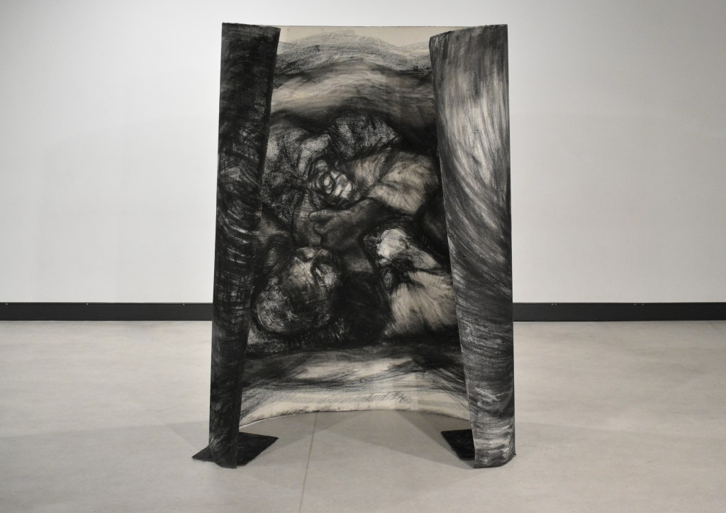 A dual-sided charcoal drawing mounted on a custom wooden stand, featuring abstract forms and textures.